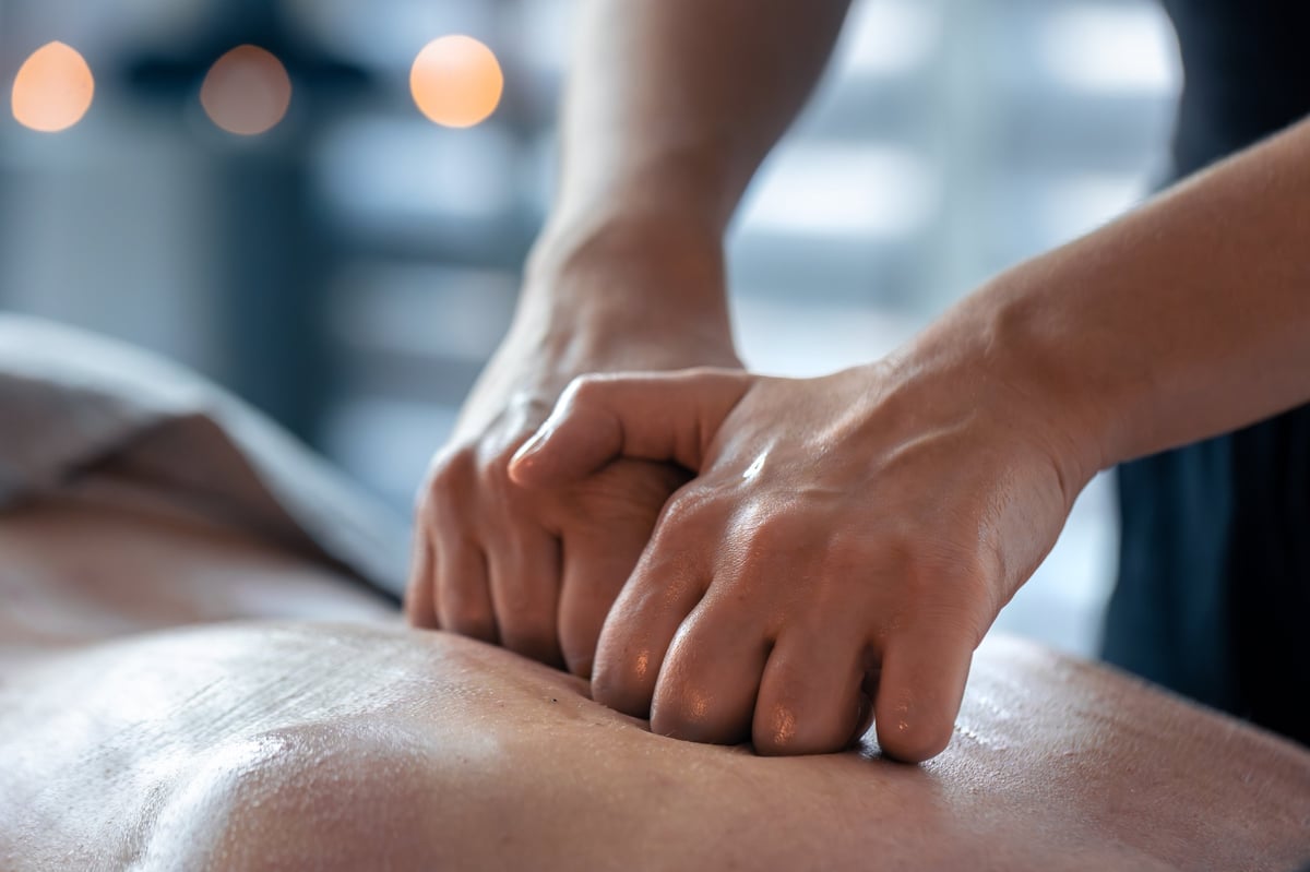 Manos presionando suavemente una espalda con aceite durante un masaje terapéutico para equilibrio y recuperación