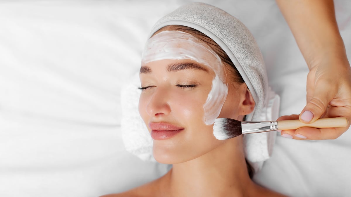 Mujer recibiendo tratamiento facial profesional con mascarilla, vista superior en spa de lujo