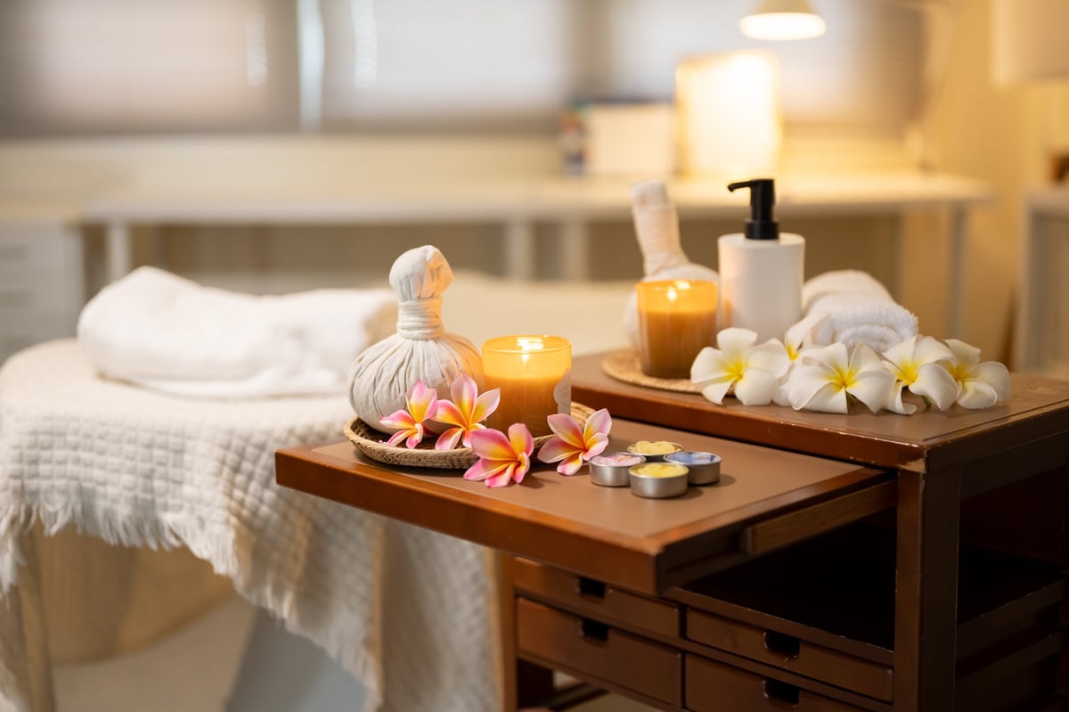 Sala de masaje con velas, compresas herbales y flores — ambiente de aromaterapia y relajación